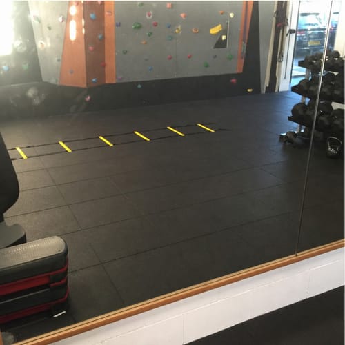 Customer photo: black rubber gym mats in a commercial gym with a climbing wall and agility ladder