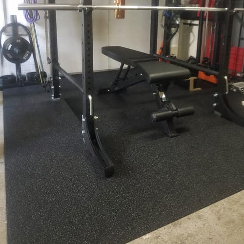 Customer photo: fleck rubber gym flooring under a squat rack and bench in a garage gym